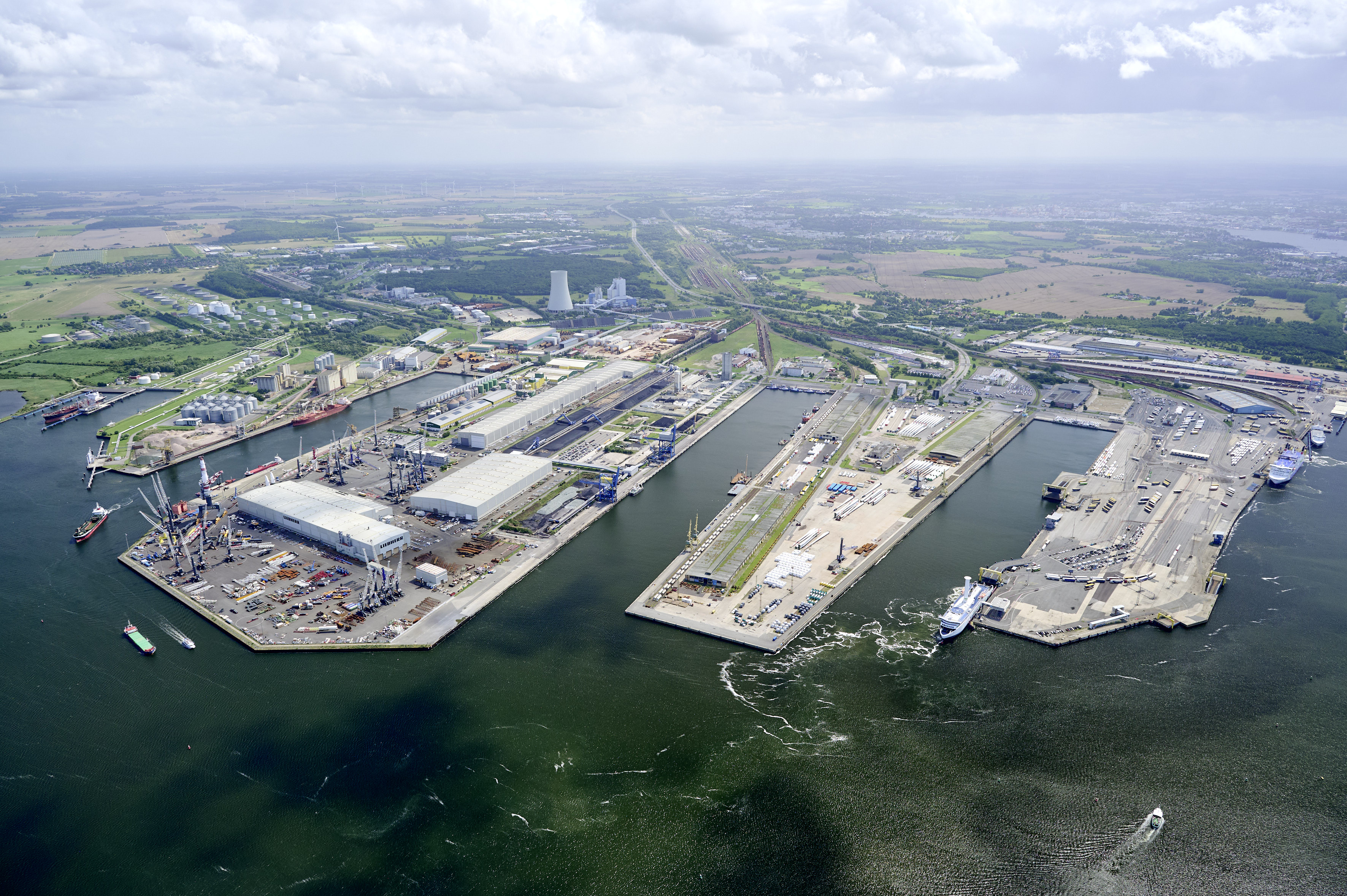 Luftaufnahme des Überseehafens Rostock mit Kaianlagen, Industrie- und Logistikflächen sowie Schiffen im Hafenbecken.