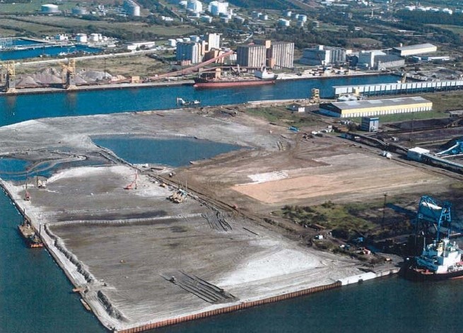 Luftbild der Hafenerweiterung auf Pier 3 nach erfolgter Sandaufschüttung vor der Kulisse des Schüttgutterminals im Hintergrund