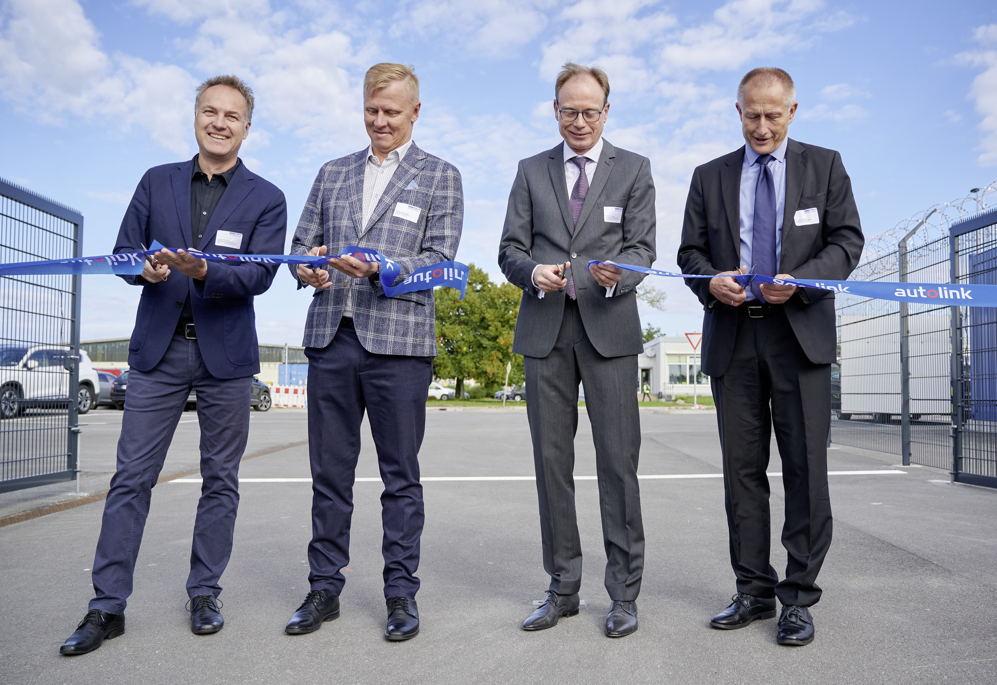 Vier Männer schneiden im Rahmen einer Eröffnungszeromonie ein Band durch.