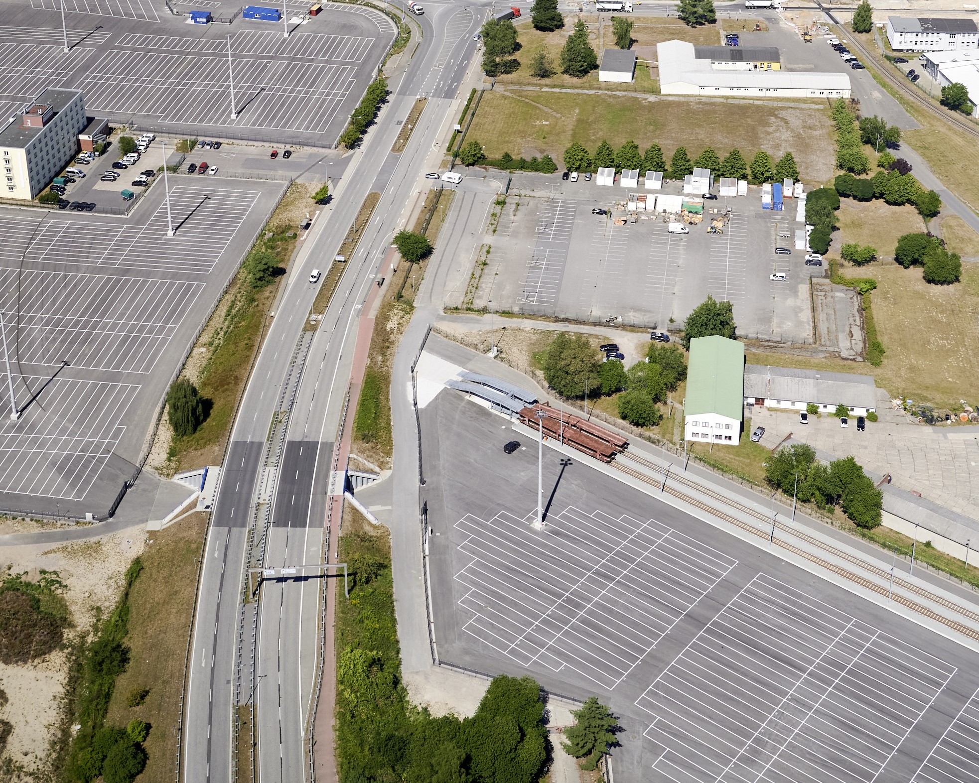 Luftaufnahme der fertiggestellten Straßenunterführung zwischen dem Autoterminal. Auf der Vorstellfläche stehen noch keine Autos.